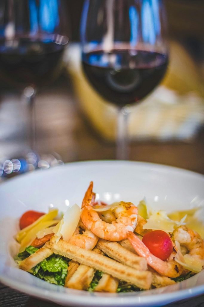 Elegante ensalada de camarones con maridaje de vinos, una comida gourmet perfecta para ocasiones especiales.